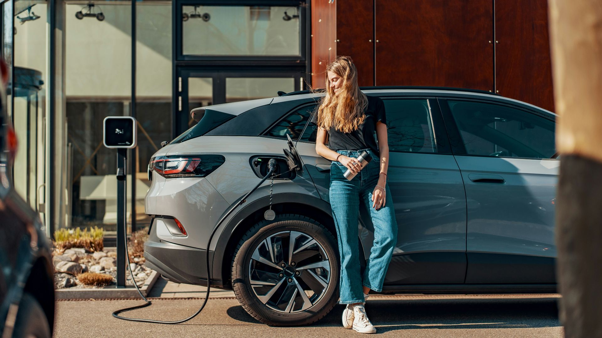 a woman standing next to a blue car