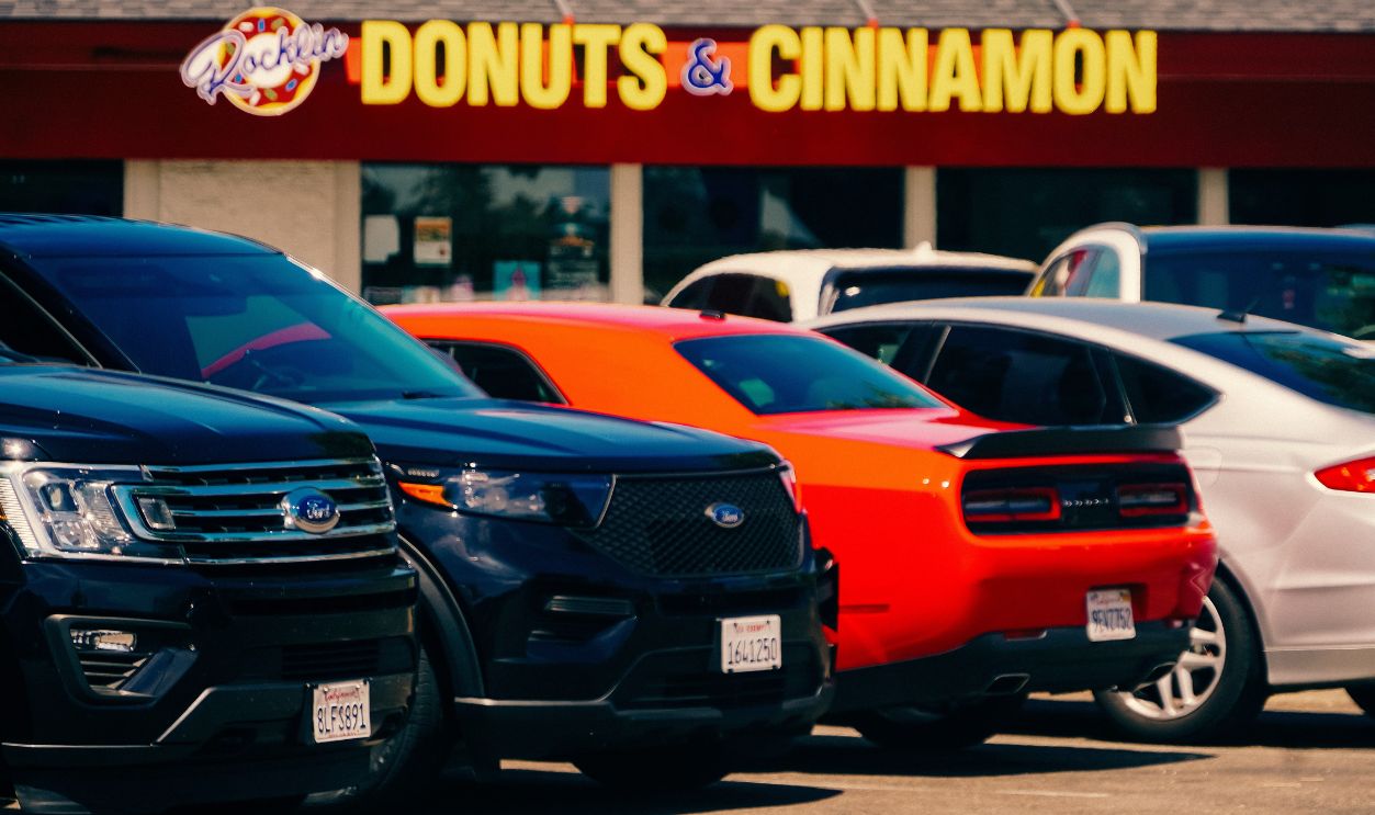 Colorful cars parked outside a Donut & Cinnamon shop in California, USA.