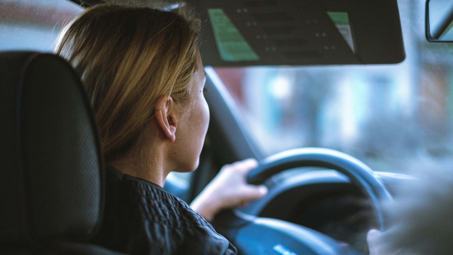 a woman sitting in a car with a steering wheel