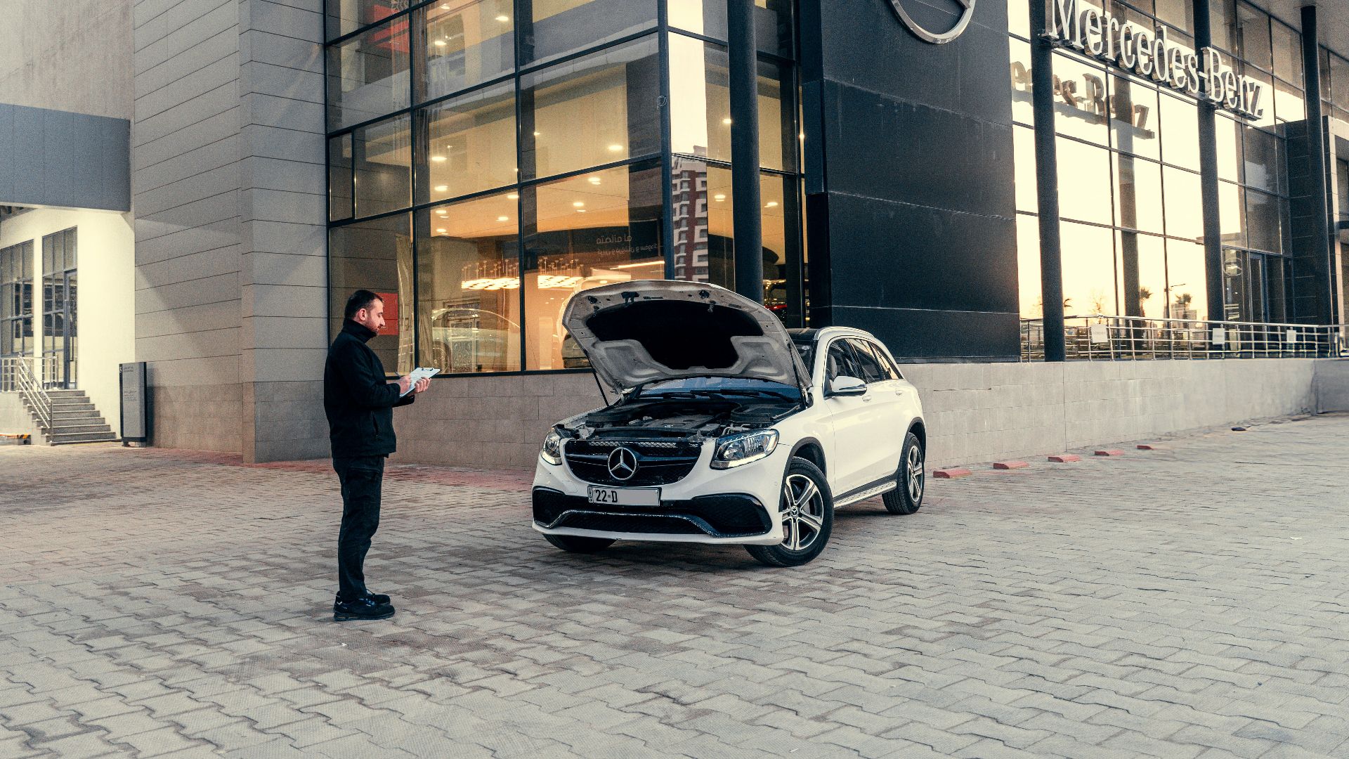 Man looking at car with hood open outside dealership