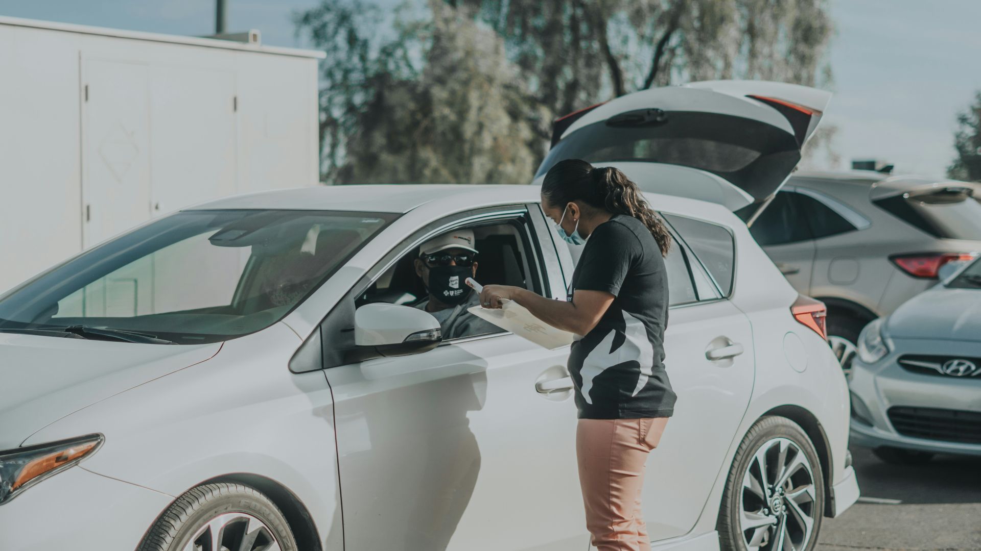 woman in black and white shirt and orange shorts leaning on white car during daytime