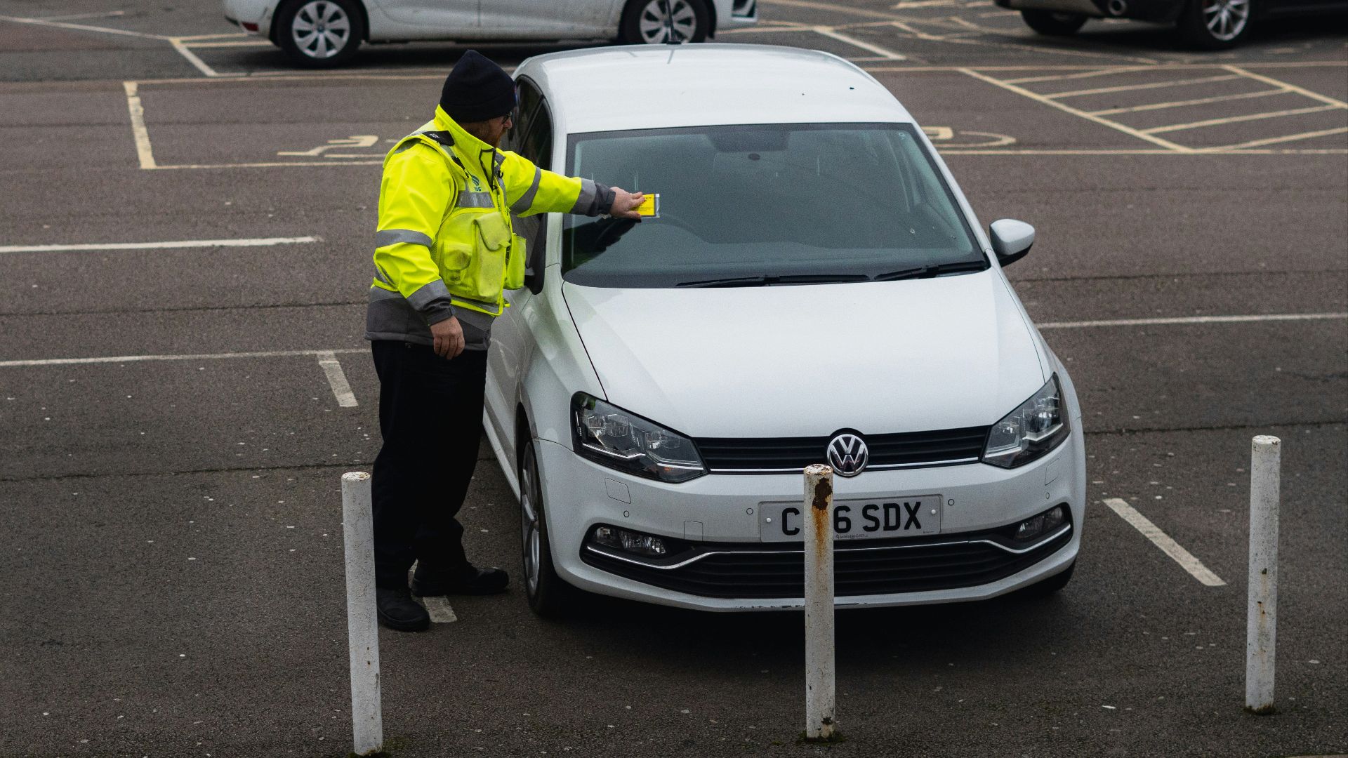 man in yellow jacket standing beside white car