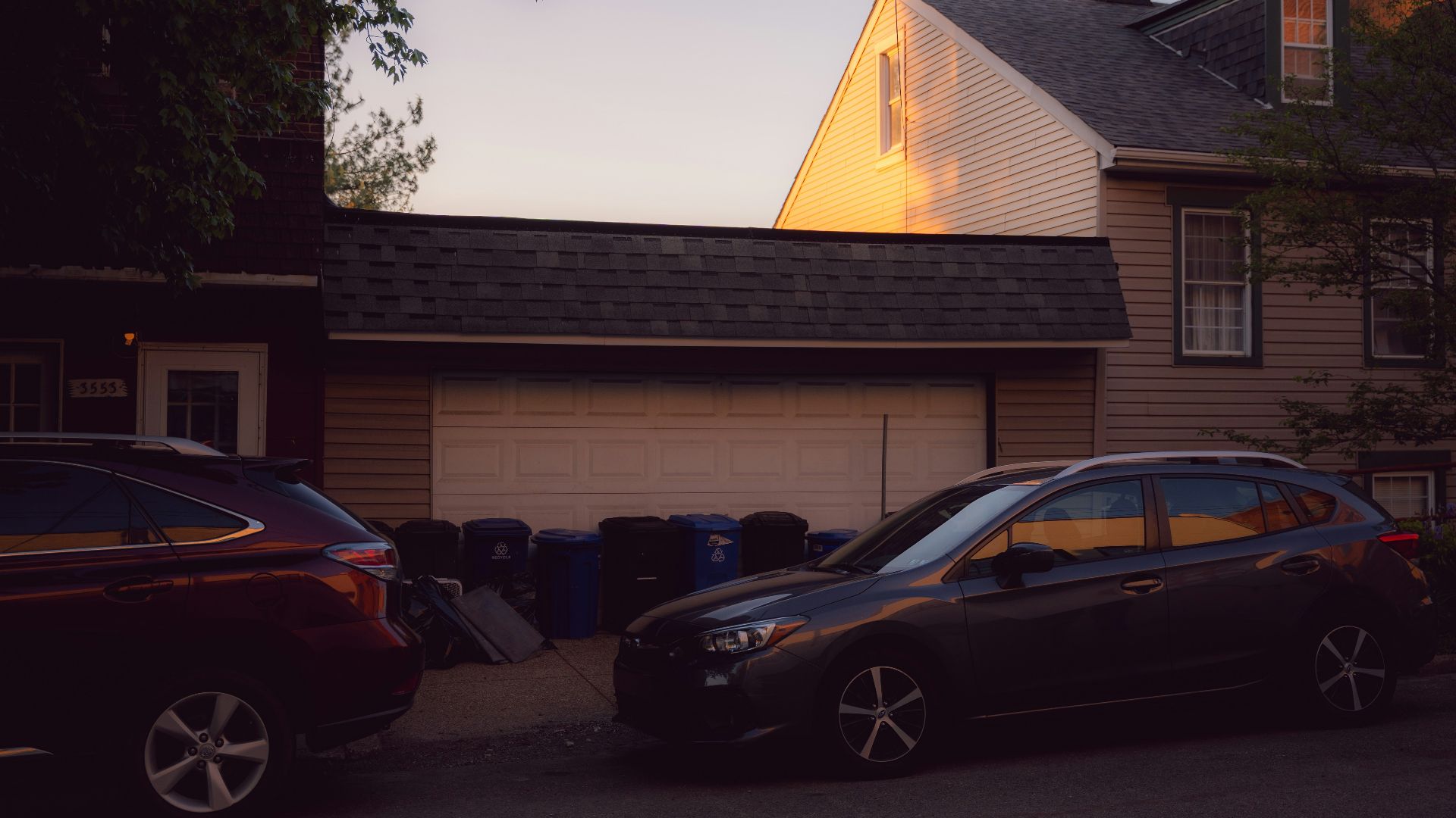 Residential street with parked cars and houses at sunset