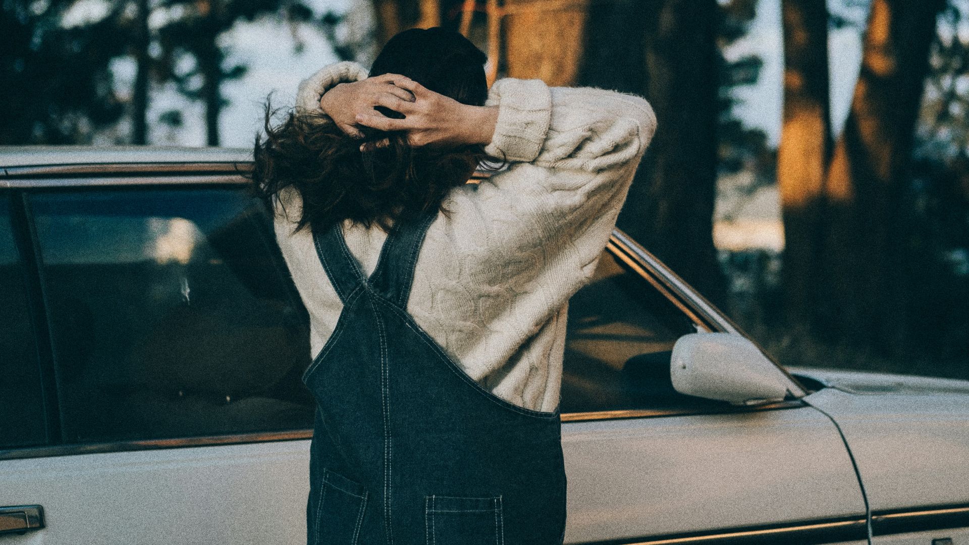 woman in gray long sleeve shirt standing in front of white car