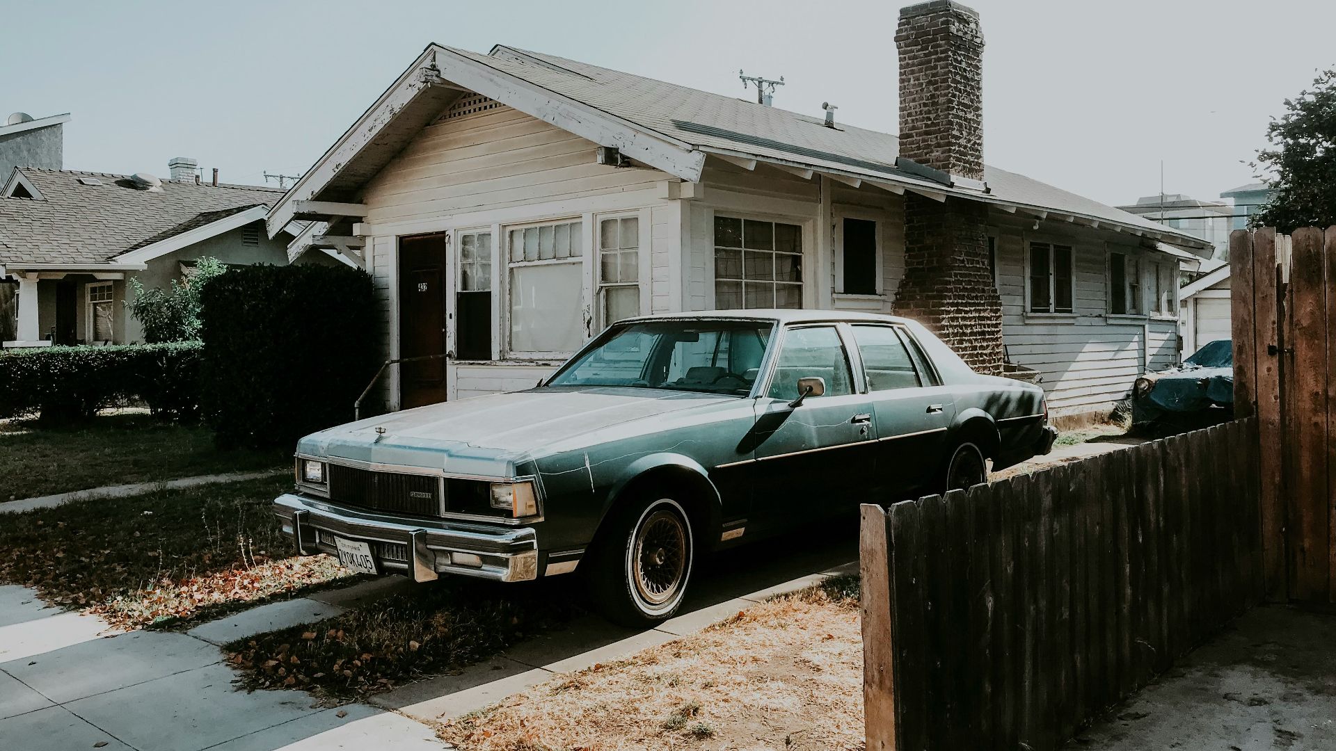 black sedan parked beside brown wooden fence