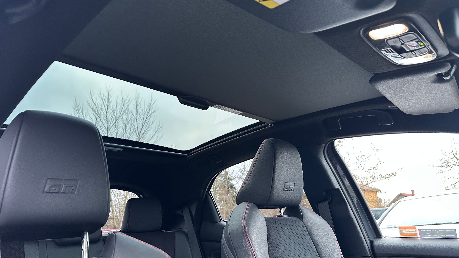 Front seats and panoramic glass roof in the interior of a Toyota Yaris GR Sport, viewed from the rear seats.