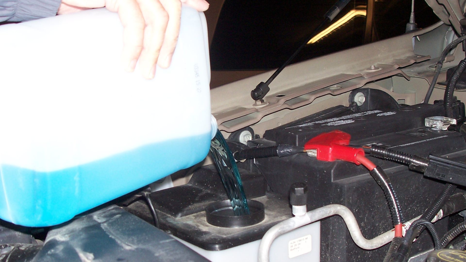 A man pouring windshield washer fluid into his car in Canada.
