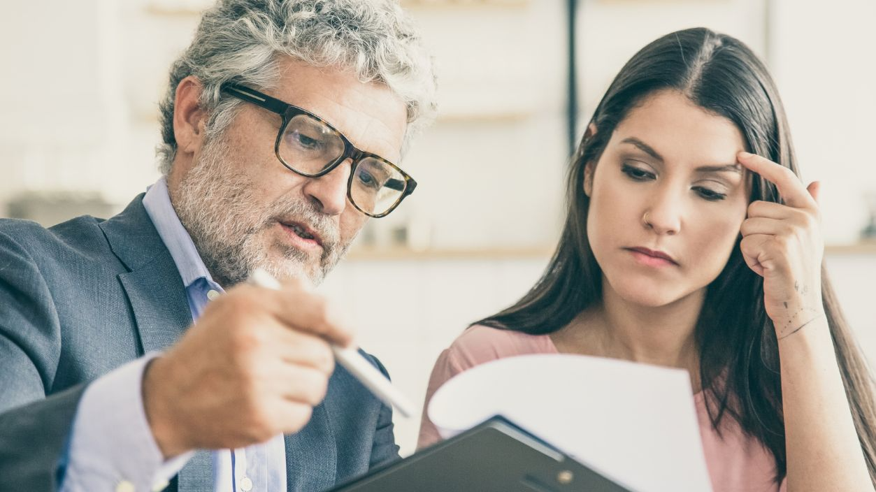 Shutterstock-1914743035, Serious mature legal advisor reading, analyzing and explaining document to female customer. Man and woman sitting at table and reading papers. Expertise and paperwork concept