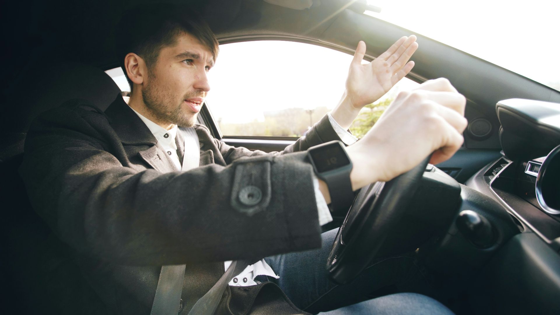 Man driving a car, gesturing with hand