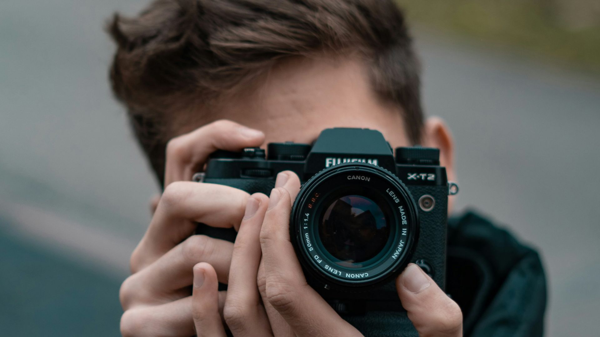 man in blue long sleeve shirt holding black nikon dslr camera