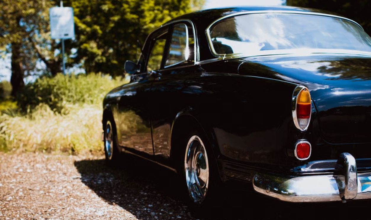 Classic black vintage car parked outdoors on a sunny day, featuring polished chrome details and retro styling.