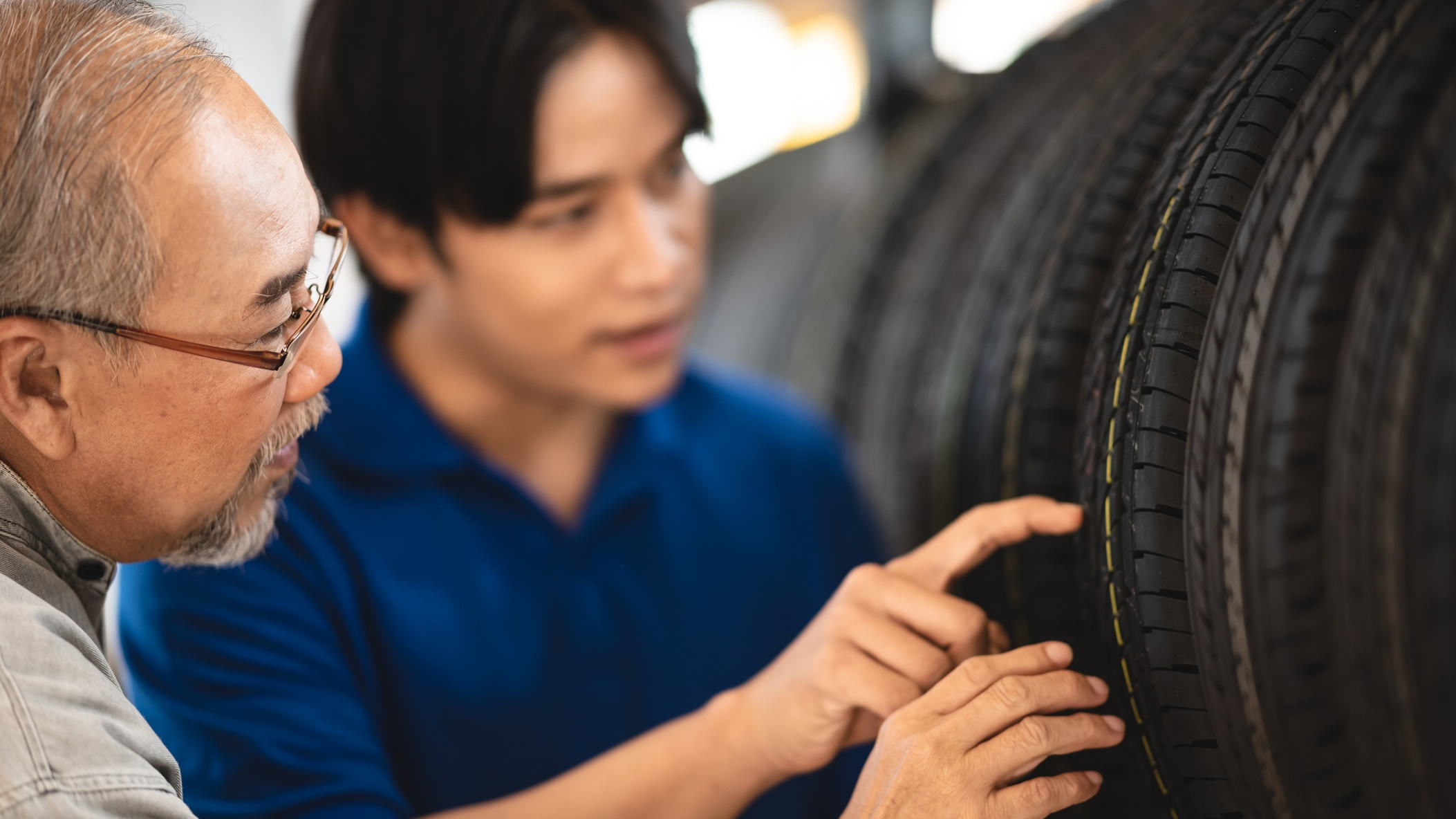 Young Asian male garage representative in conversation with senior customer