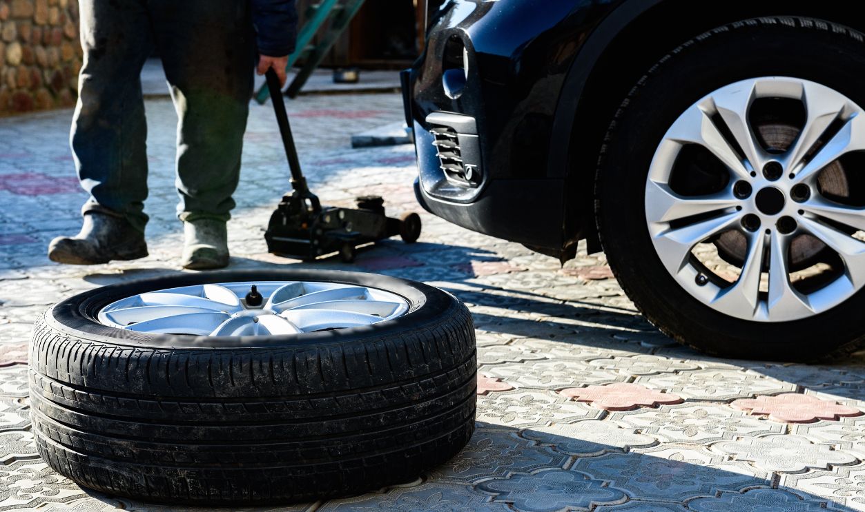 Changing wheels and tires for a car according to the season. Unscrewed wheel on the background of a parked car in the yard.