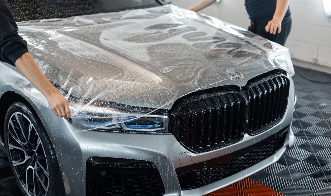 Professional master man the car with protective ppf film in detailing service. Protection and care of the car. Wrapping car