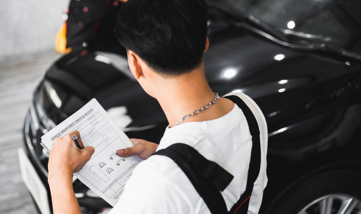 Car wrapping specialist checking vehicle maintenance document before doing PPF installation process on a front headlight and hood. PPF installation process on a front headlight and hood. 