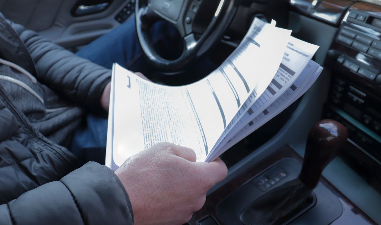 Man with car documents. Making a loan for a car. Car rental with the necessary documents. Insurance documentation for cars.