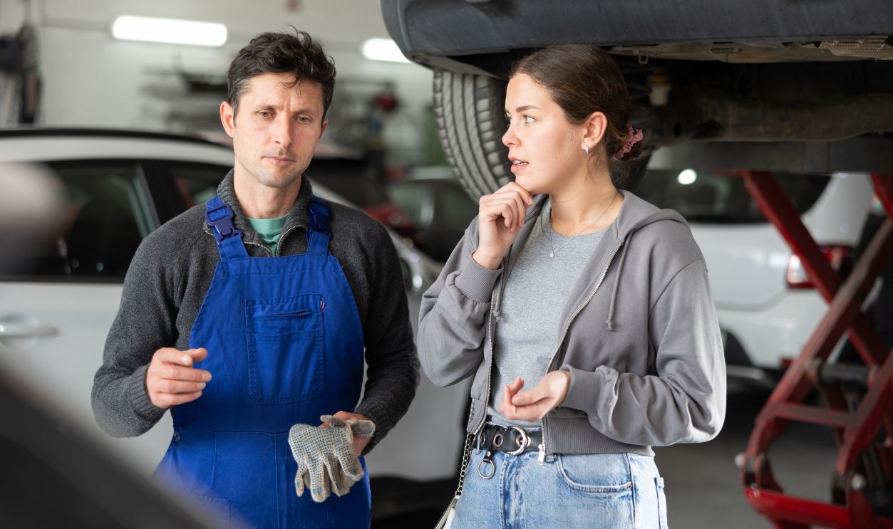 Shutterstock-2588727967, Man car mechanic talks with girl client in workshop and takes order. Customer explains details of order to contractor and talks about problem with car.