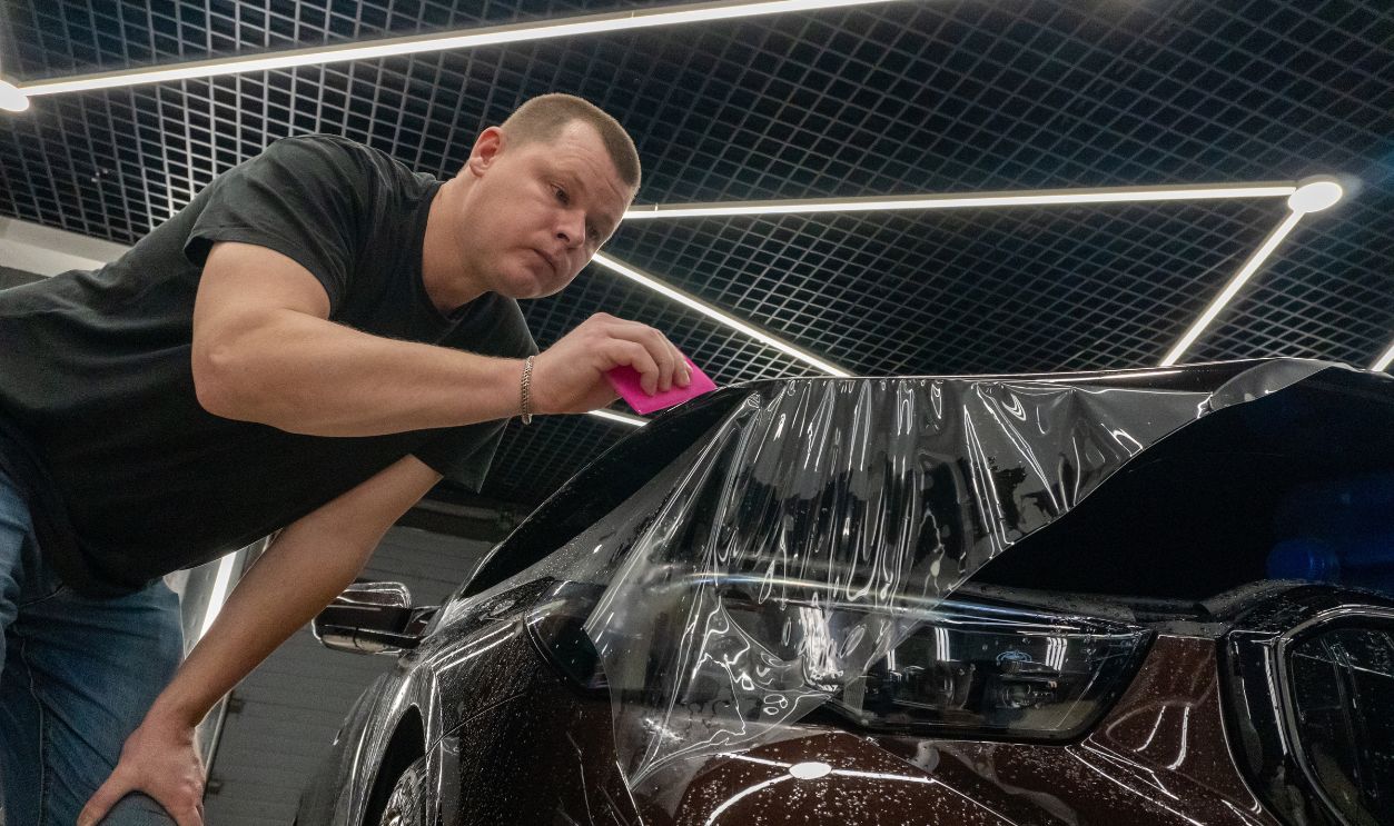 St-Petersburg, Russia,February 15, 2025: The process of installing PPF on the side of the car. PPF is a polyurethane, protective film that protects the paint from scratches and gravel. Car tuning. 