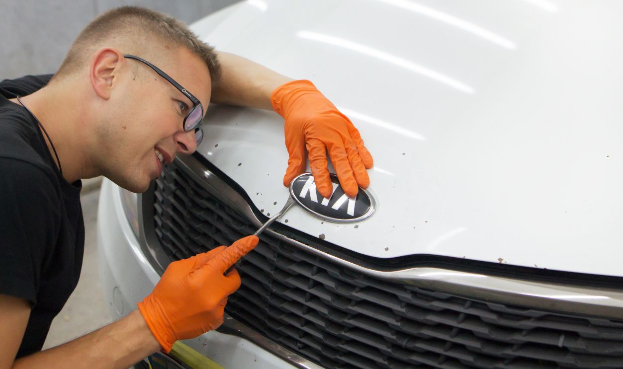 GOMEL / BELARUS - OCTOBER 8, 2018: a handsome guy with glasses cleans up a badge on a cue car with orange gloves