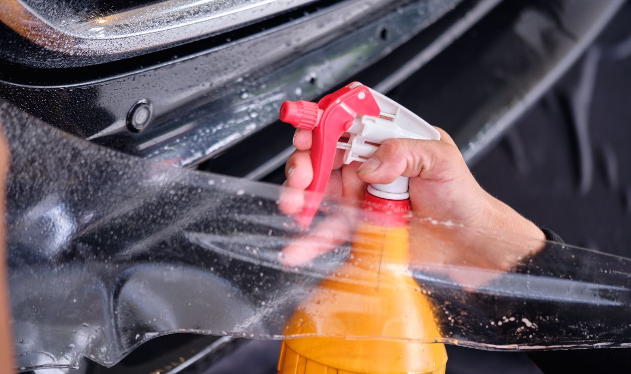 Paint protection film installation on fender panel surface of luxury sports car. PPF is polyurethane film applied to car surface to protect the paint from rock chips, marks and scratch. Shallow DOF.