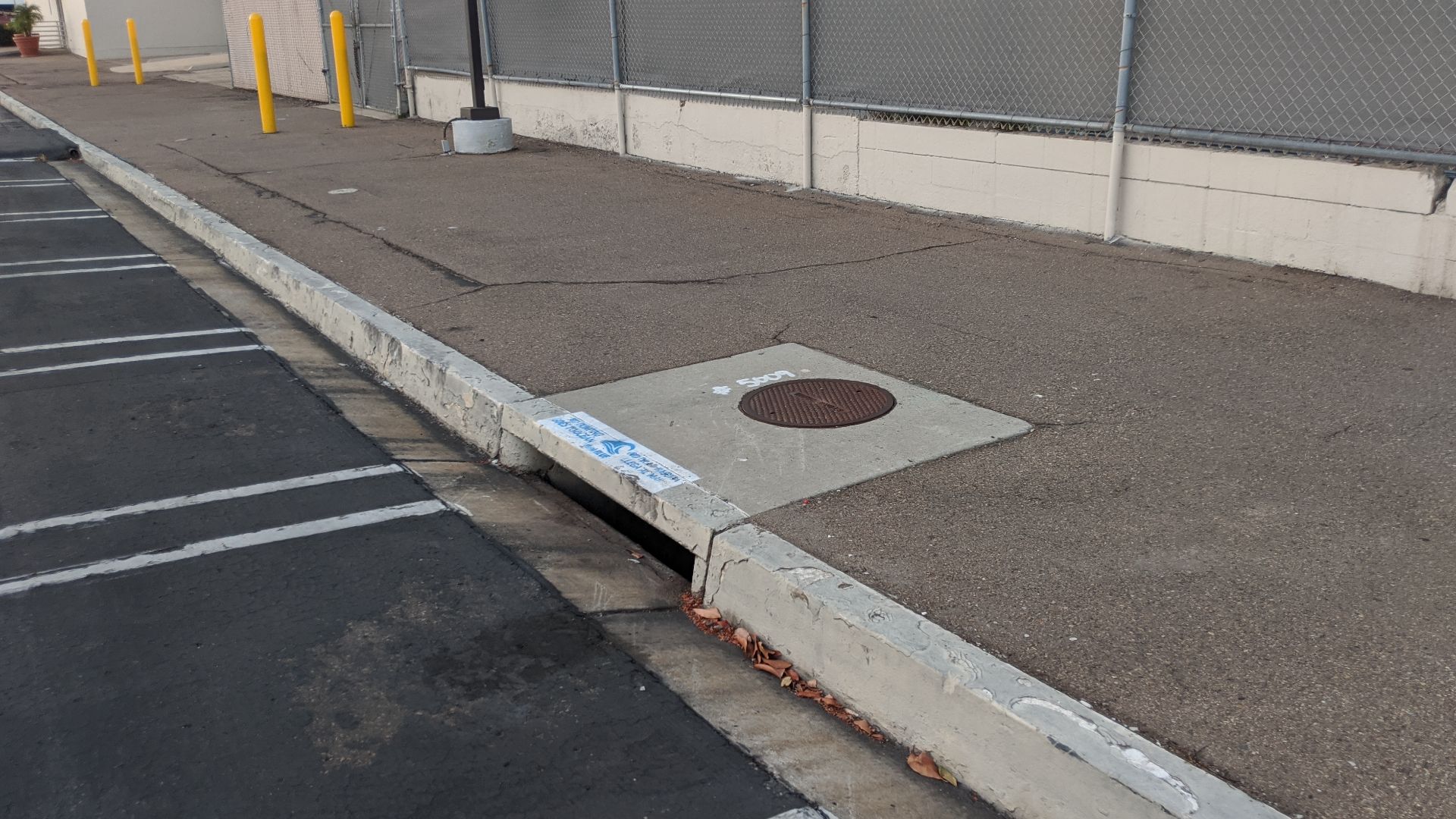 A cub inlet and catch basin in San Diego, CA, USA. A white stamp denotes that no dumping should occur as the storm drain discharges to the ocean.