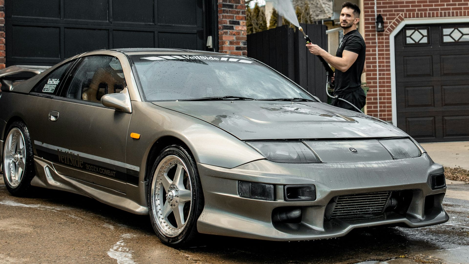 Man washing grey sports car on driveway