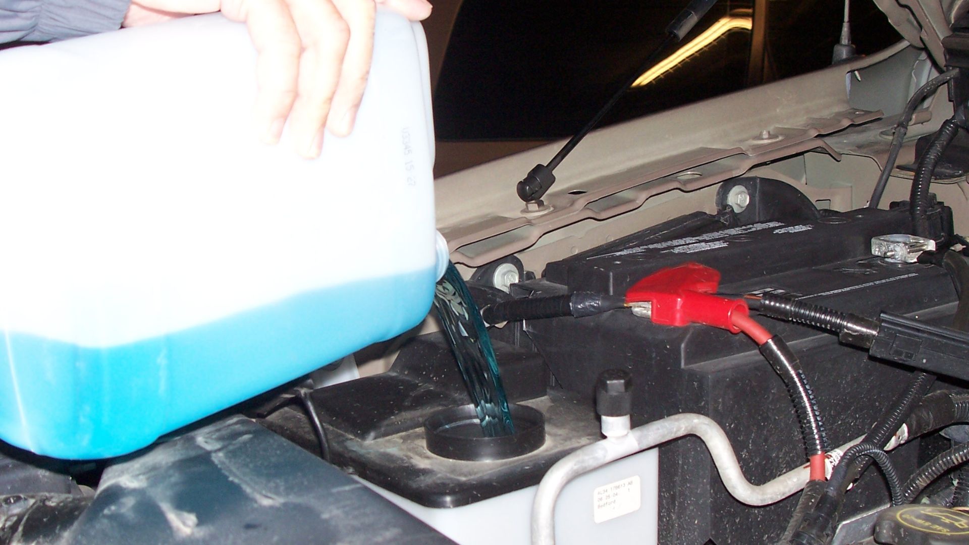A man pouring windshield washer fluid into his car in Canada.