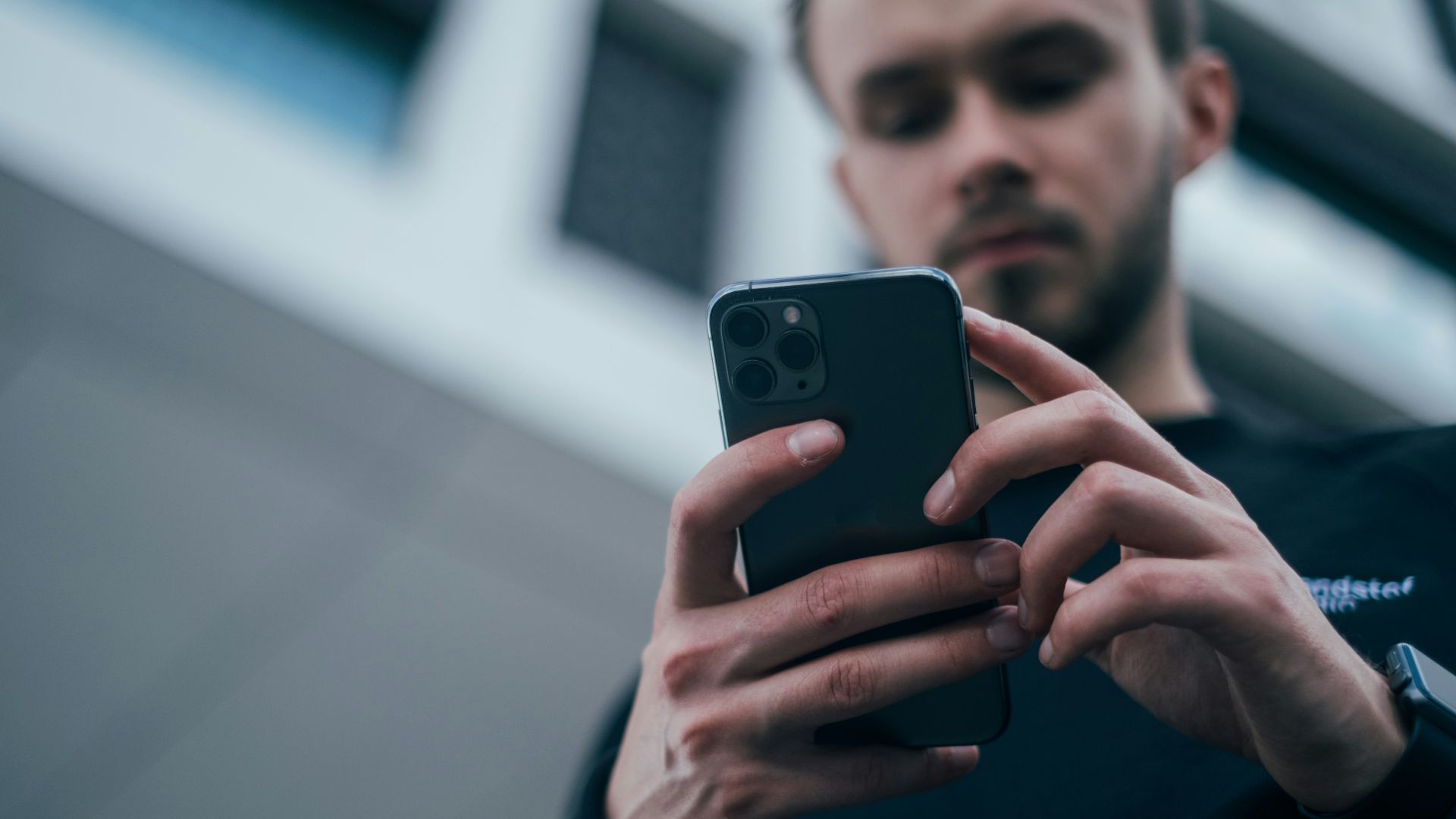 man wearing black sweater using smartphone