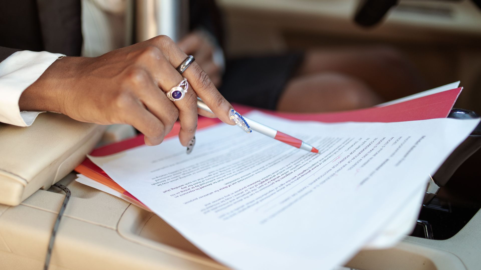 A professional reviewing documents in a car interior, focusing on hand and paperwork.