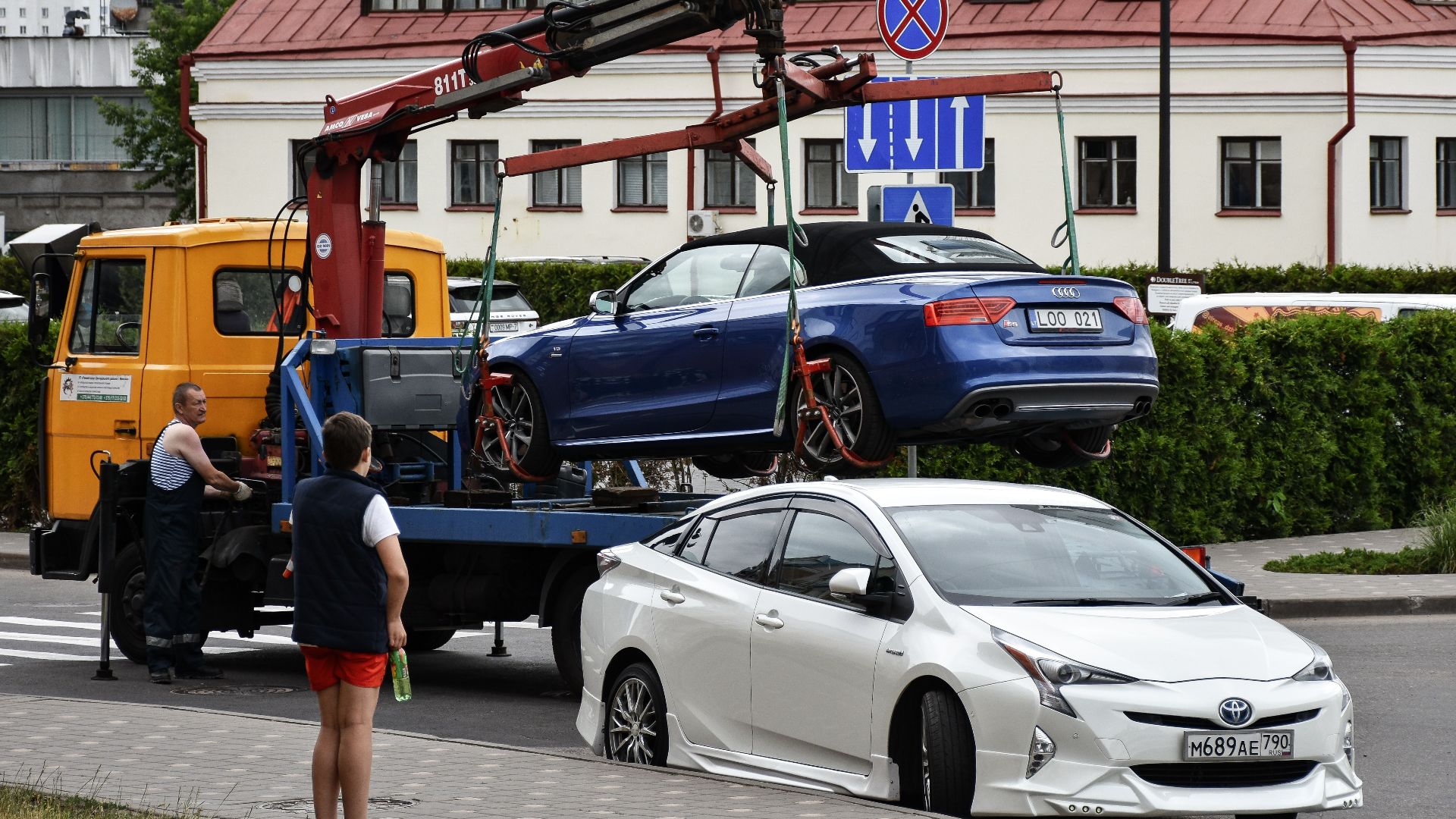 Towing a blue Audi convertible in a bustling city street.