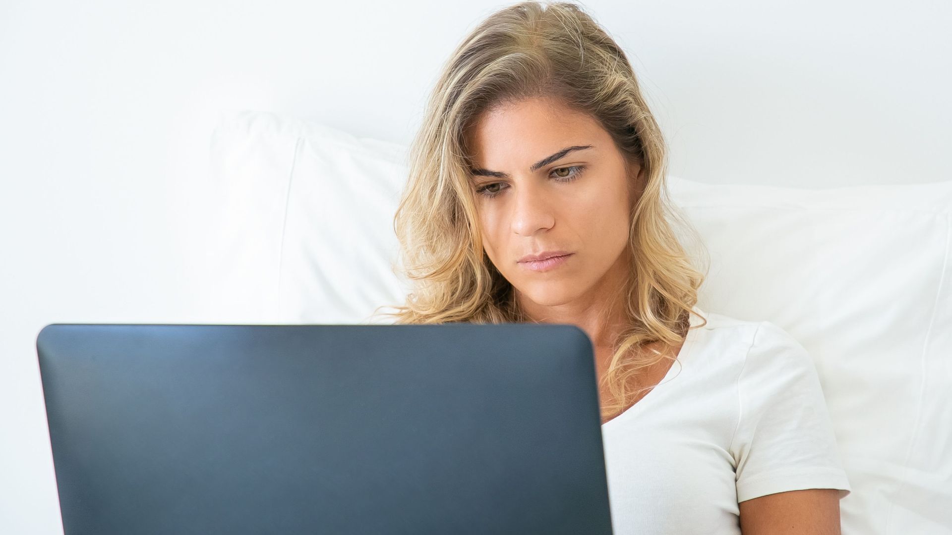 A woman attentively working on her laptop while sitting comfortably at home, showcasing remote work lifestyle.