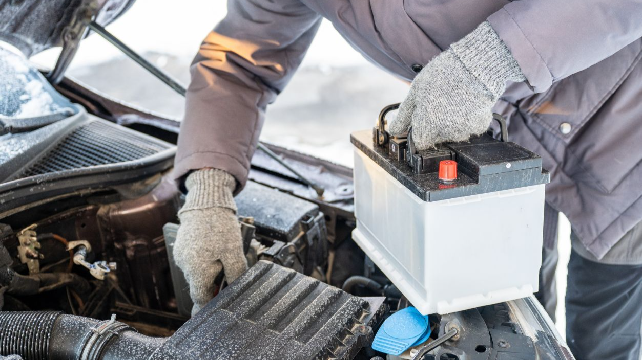 Man replacing car battery in winter cold with open hood during roadside emergency repair, emergency vehicle maintenance concept. High quality photo