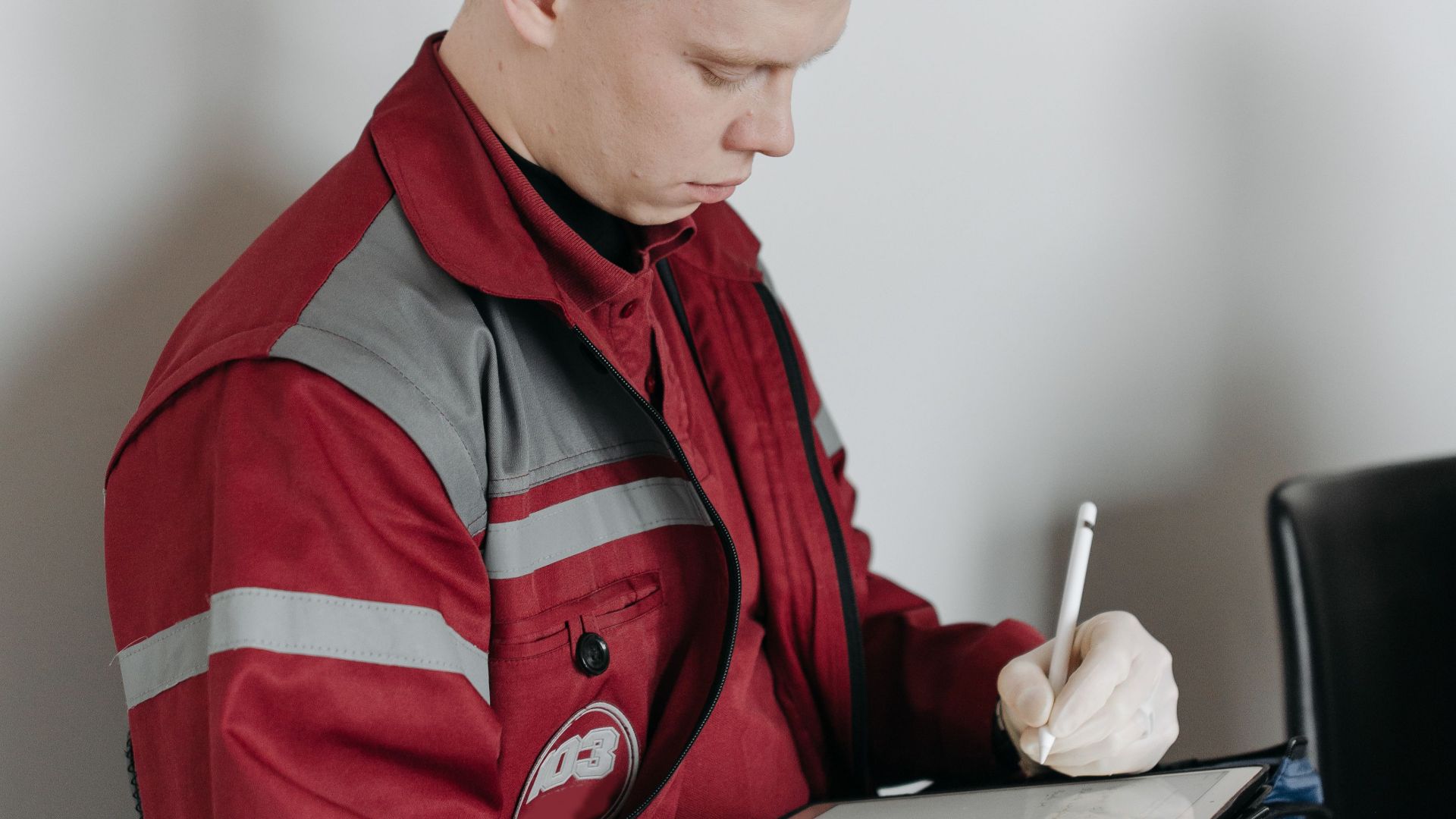 Paramedic in red uniform taking notes inside a room. Ideal for healthcare and emergency concept.