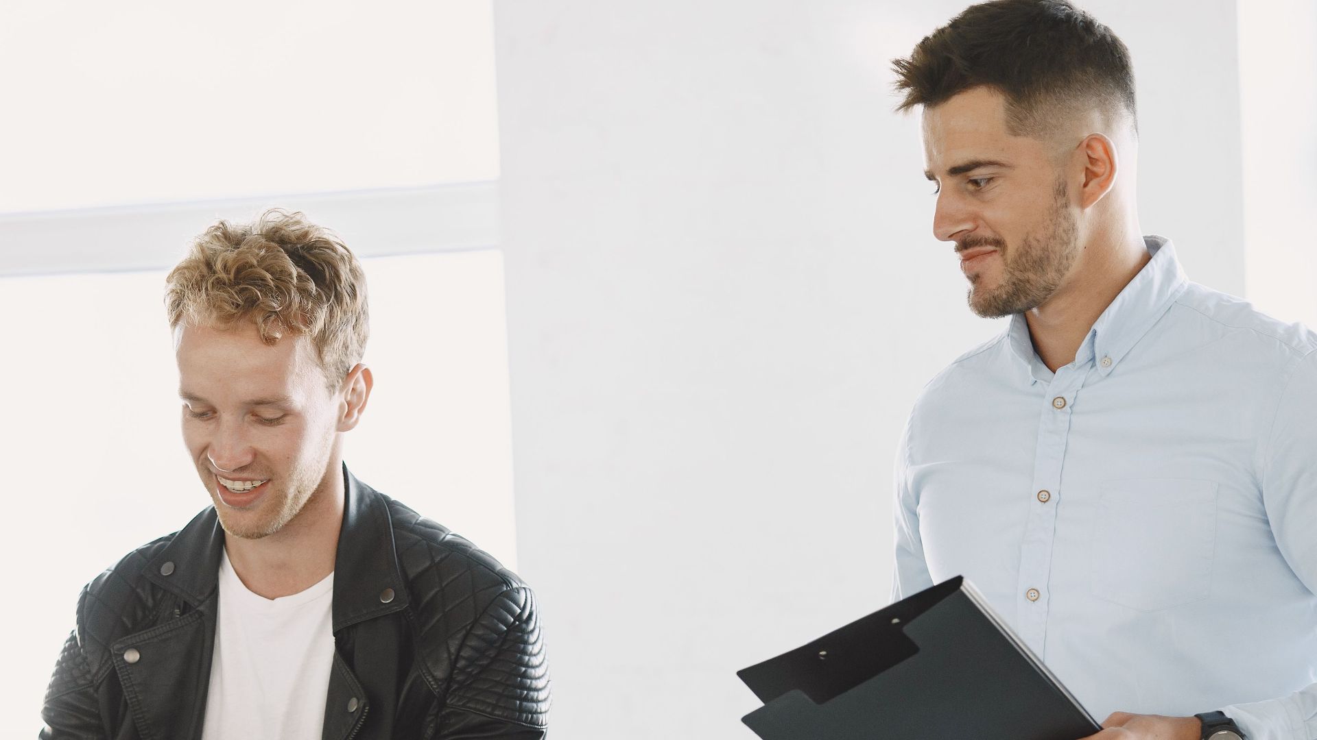 Two men at a motorcycle dealership discussing a motorbike purchase.