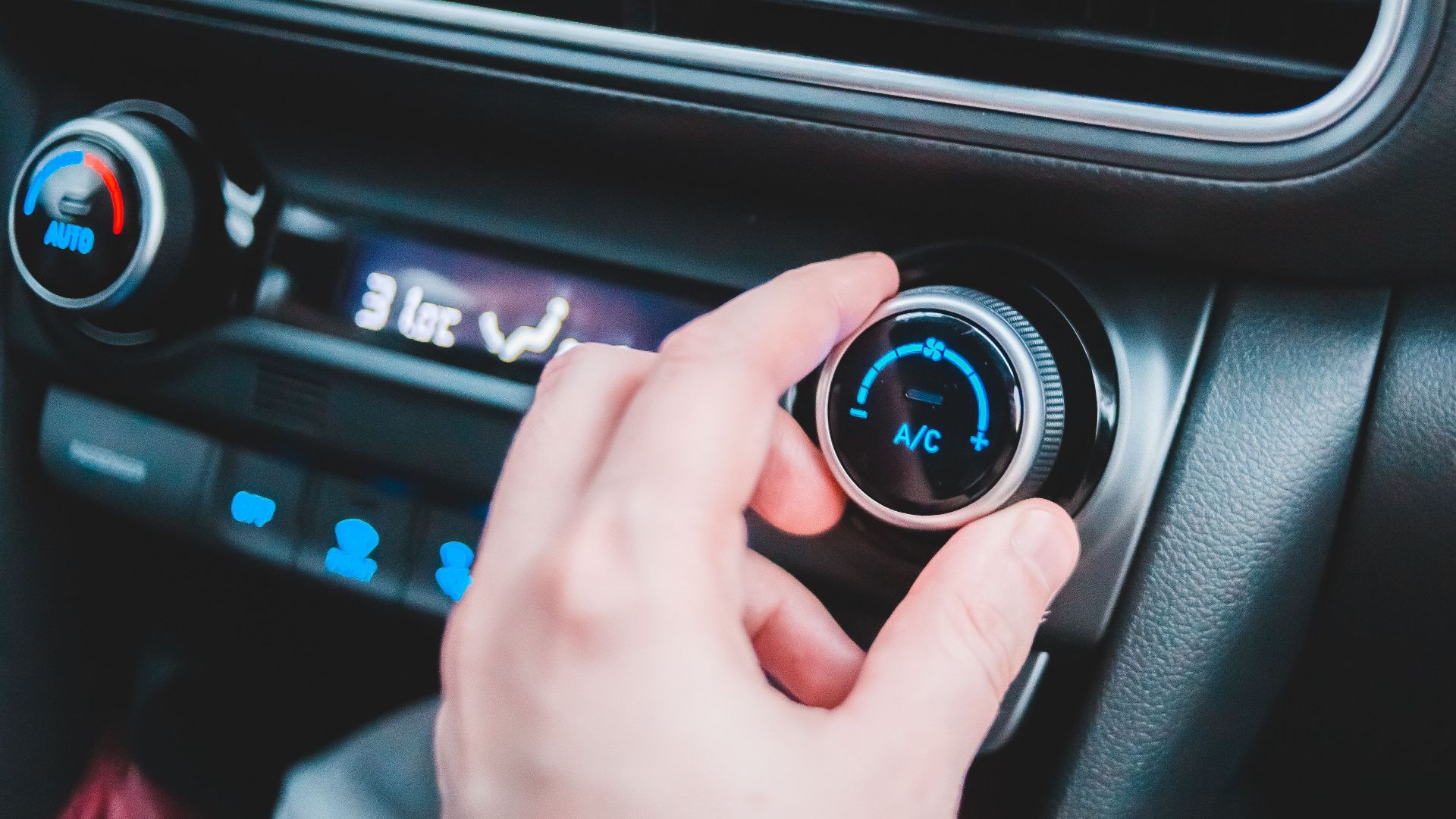 Crop anonymous person regulating temperature in car using controller on panel while sitting in car