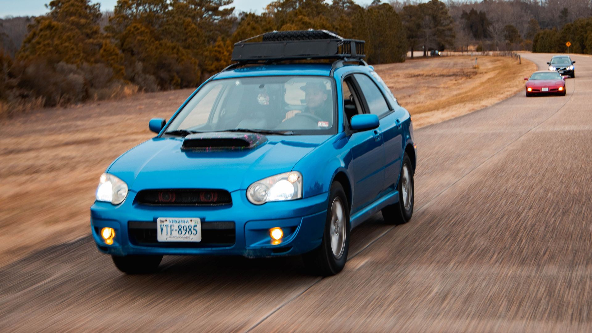 A blue sports car speeds down an open road, capturing the thrill of driving.