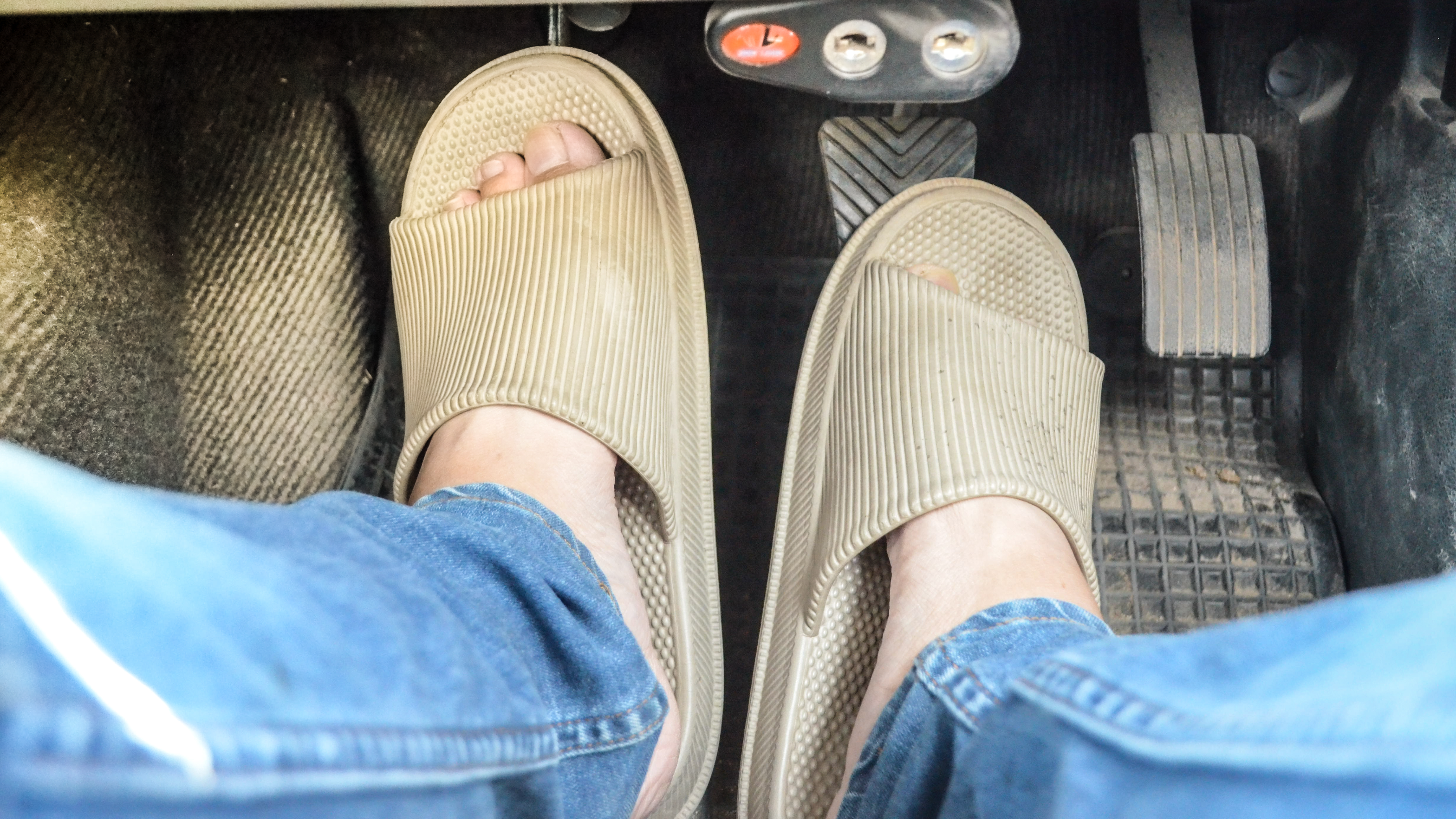 Feet in sandals on car pedals
