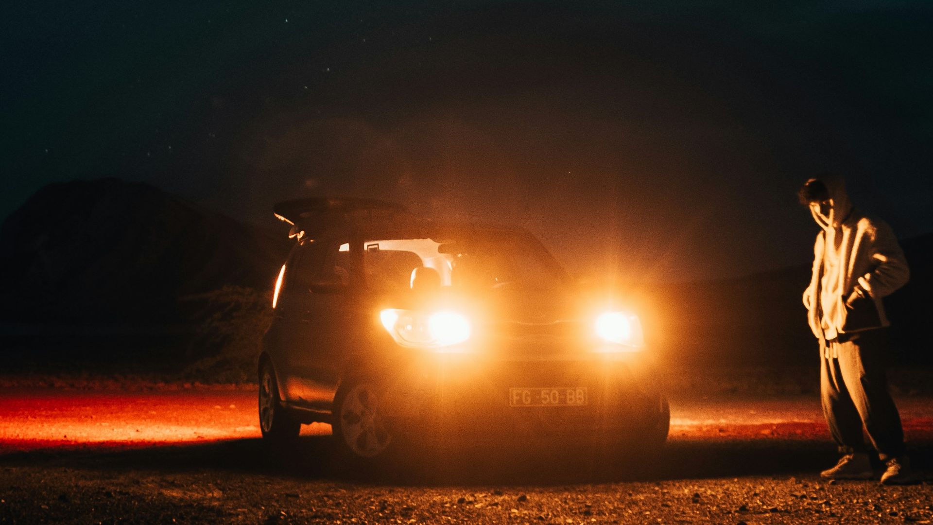 a man standing next to a car under a night sky
