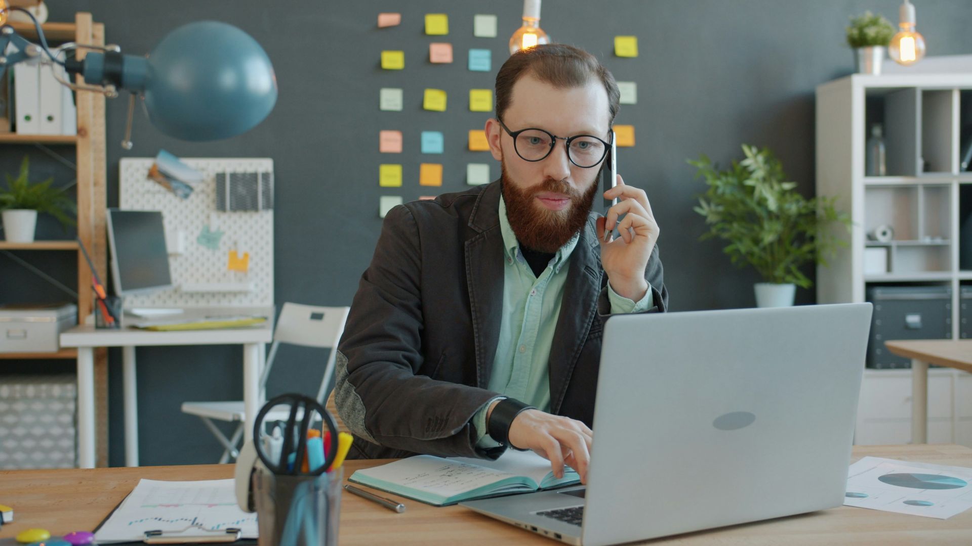 Man on phone working on laptop in office
