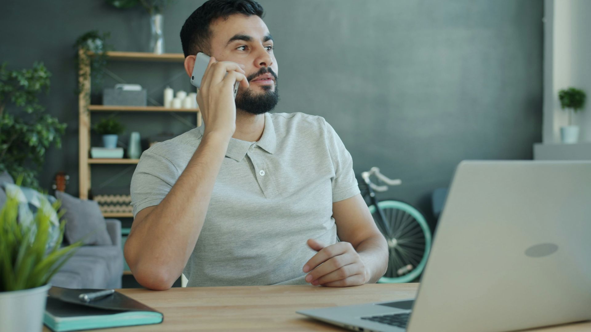 Man talking on phone at desk with laptop
