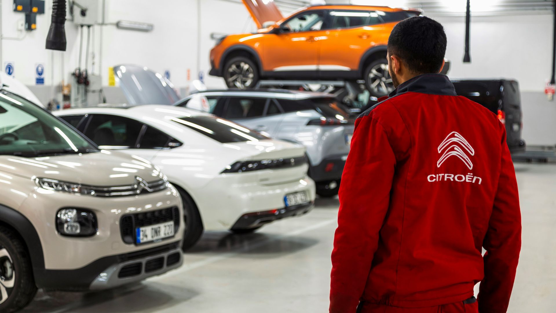 A man standing in a garage looking at cars
