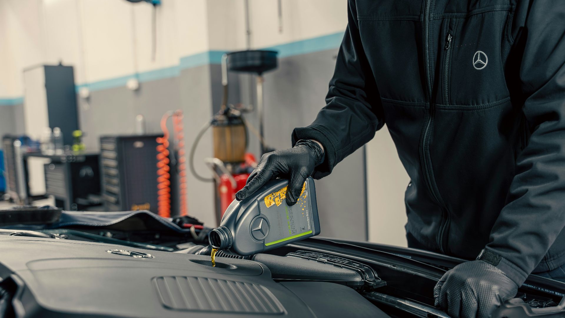 Mechanic pouring oil into car engine