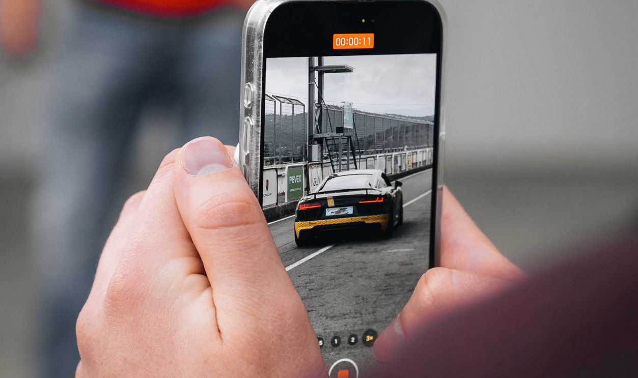a person taking a picture of a car on a cell phone