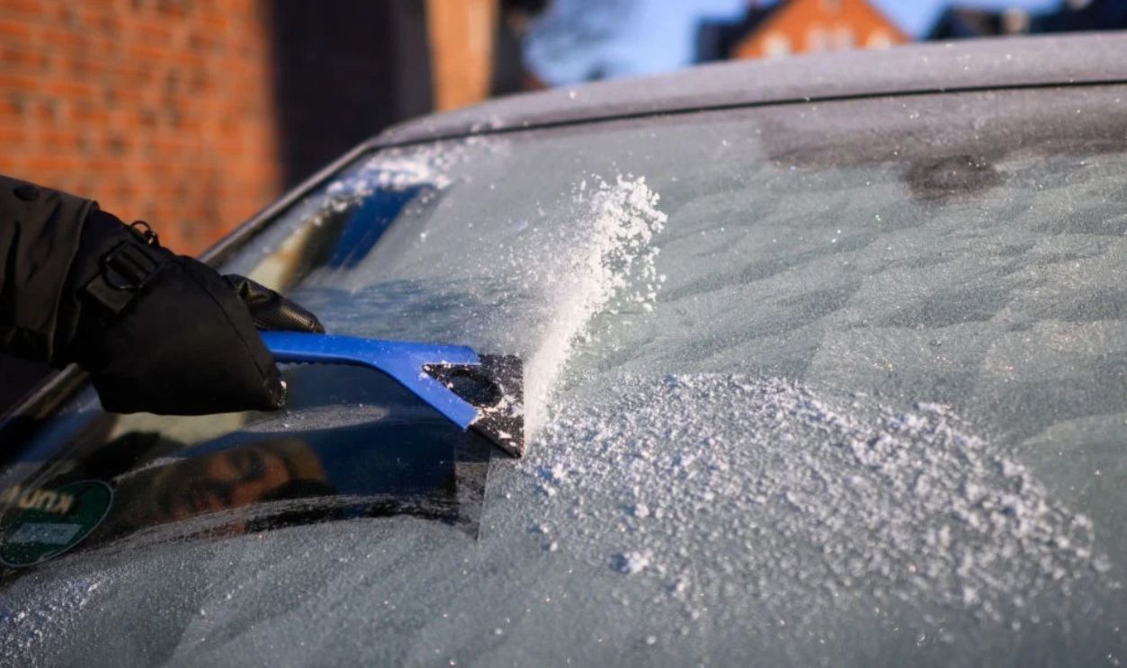 17 February 2025, Lower Saxony, Laatzen: A woman scrapes ice off the windshield of a car in the Hanover region in temperatures well below freezing. Photo: Julian Stratenschulte/dpa