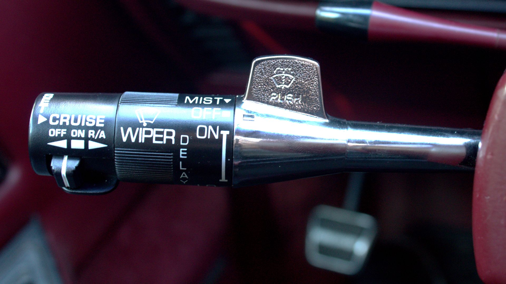A typical multi-function turn-signal lever of General Motors vehicles built in the late 1980s, here on a 1987-issue Oldsmobile Toronado Troféo. It features special switches to operate cruise control (left), wipers (middle), and the windshield washer (righ