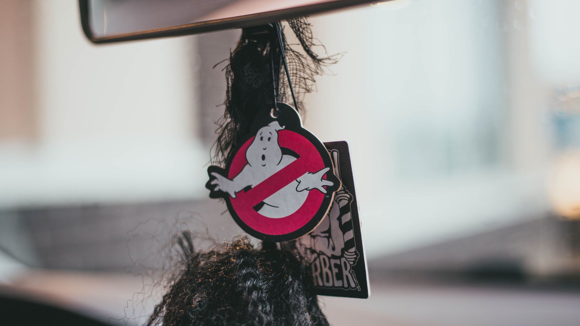 Hanging Ghostbusters themed air freshener inside a car, evoking humor and nostalgia.
