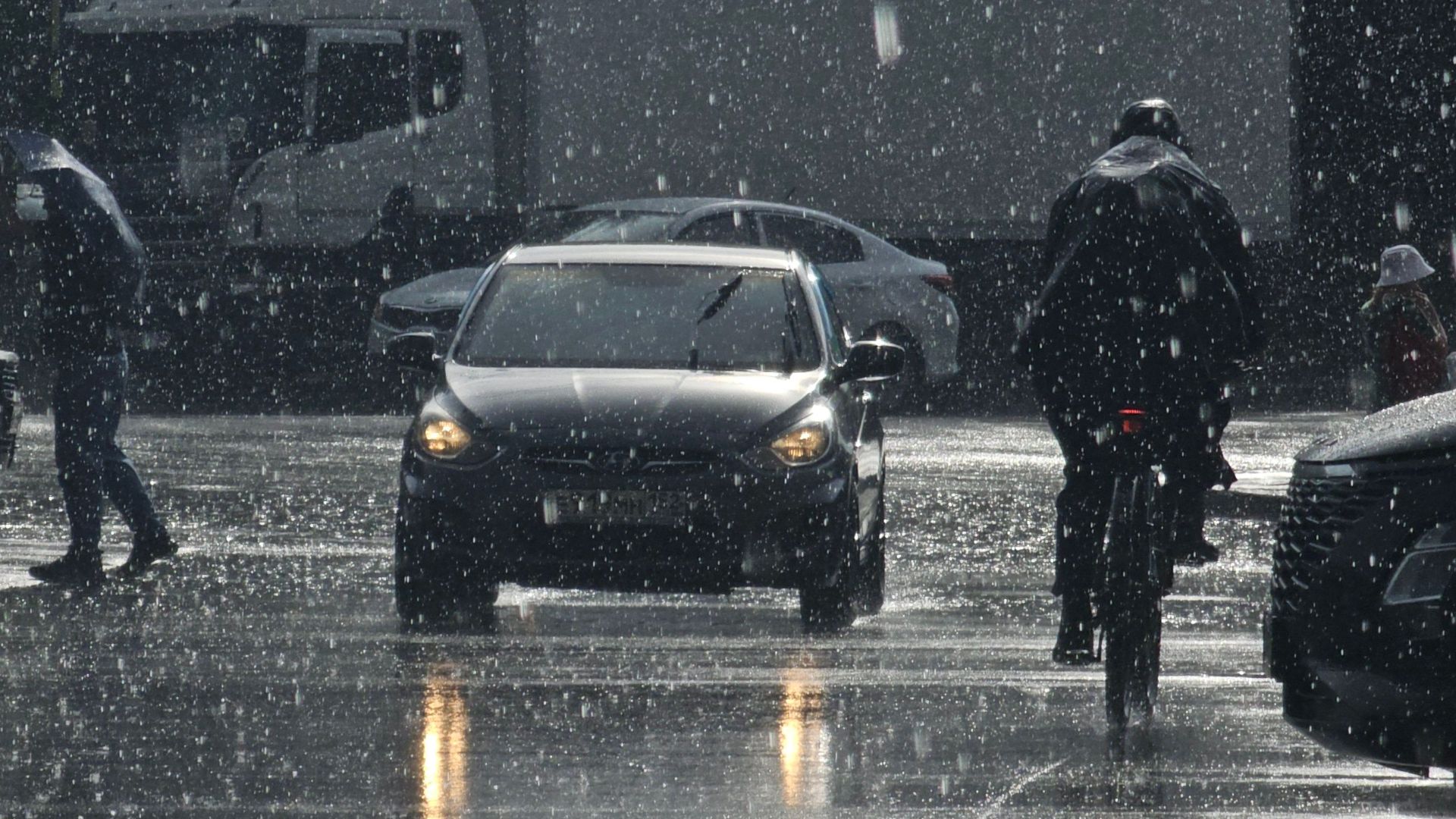 Moody urban street scene in heavy rain with cars and pedestrians.