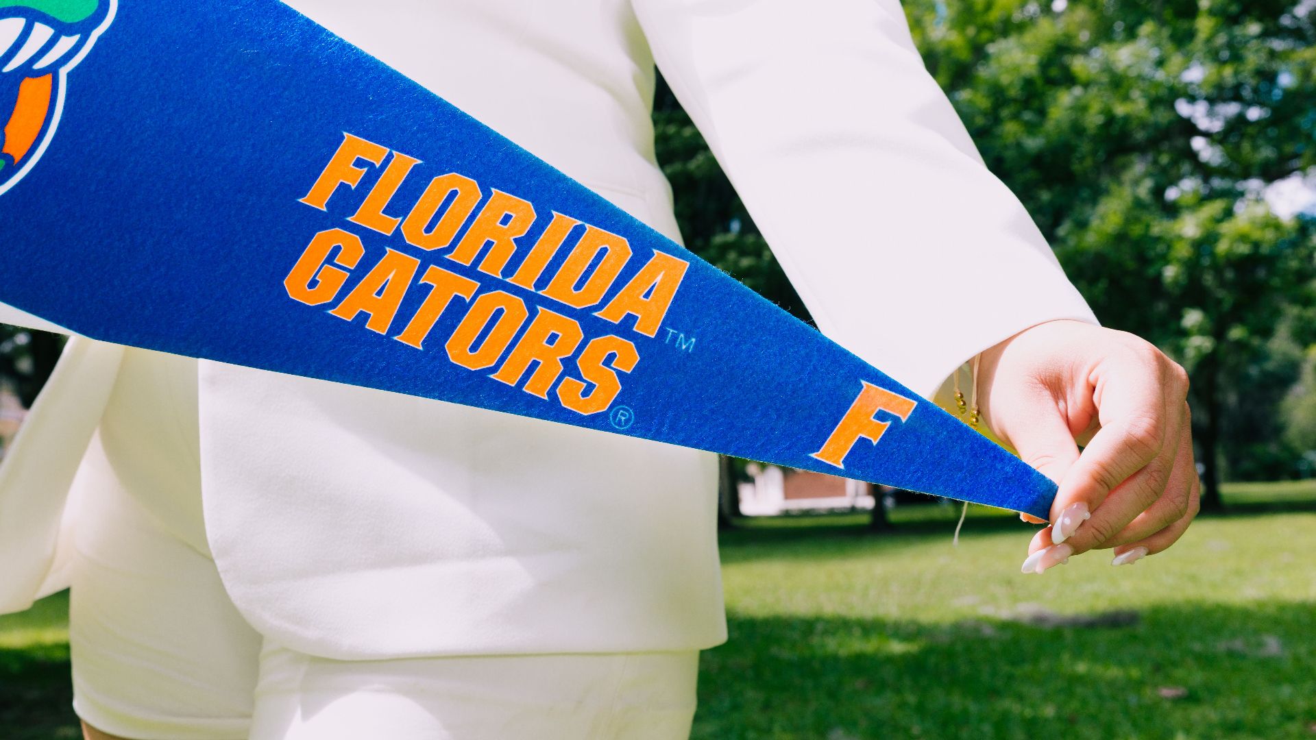 Fashionable woman holding a Florida Gators pennant outdoors in summer.