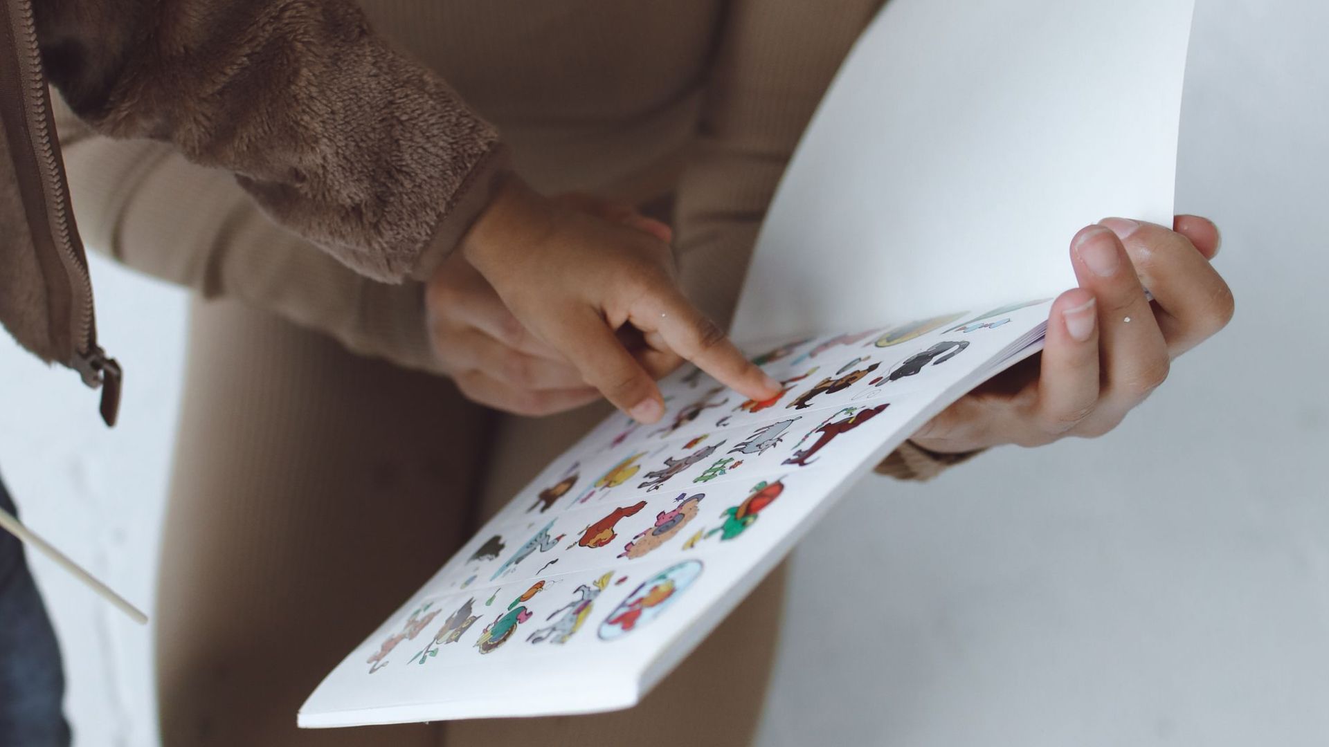 A mother and child engaging in an educational activity with a book on a white background.