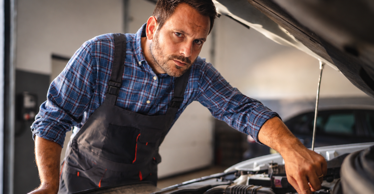 Adult man car mechanic work in a garage, use tools to repair a vehicle while the car hood is open